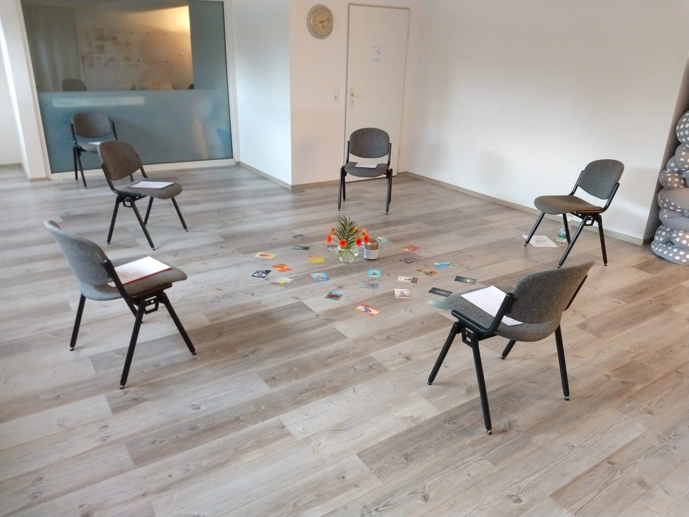 Stühle in einem Kreis um einen bunten Stapel von Materialien auf dem Boden.