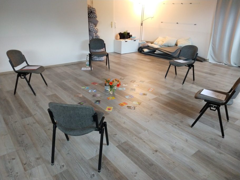 Kreis aus Stühlen um einen Blumenstrauß auf einem Holzfußboden.